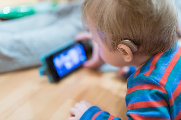 Click the photo of a baby with a hearing aid watching a video on a phone to find out how we all win with accessibility. 