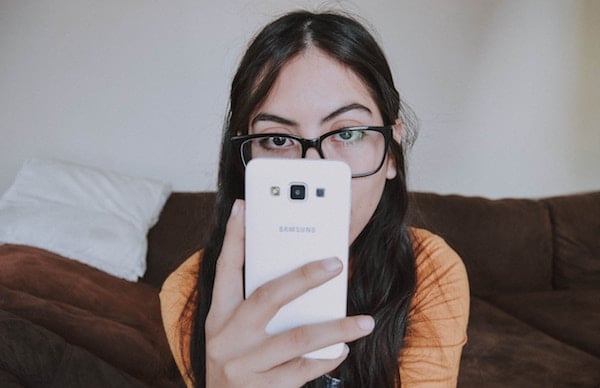 Click the photo of a woman wearing glasses using a smartphone to give feedback on the new standards. Photo by Bianca Castillo on Unsplash.