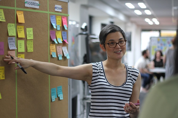 Click the photo of a Product Owner in front of a Scrum board to view the post on how Agile transparency reduces project risk. 